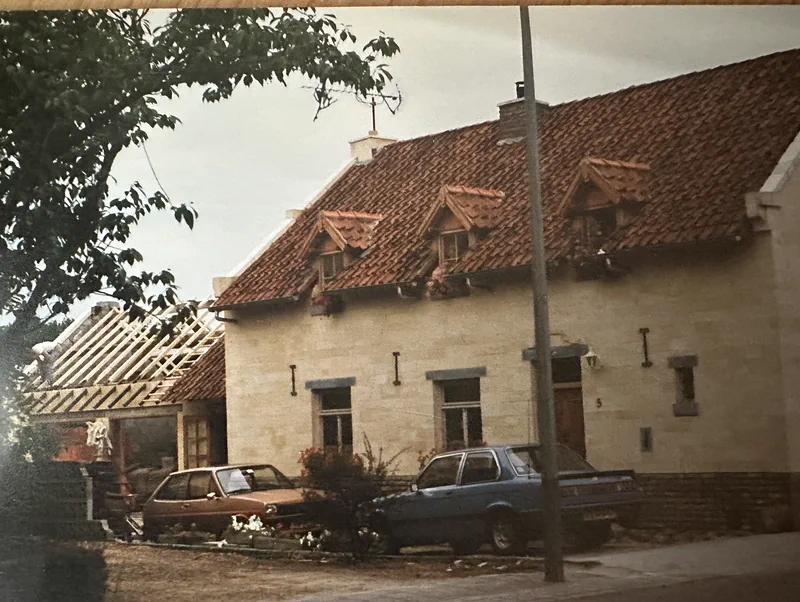 Het huis met de nieuwe gevel, twee auto's van toen ervoor en het bijgebouw nog in de steigers